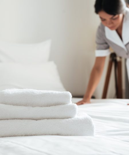 Young hotel maid making the bed with clean fresh towels Young hotel maid making the bed with clean fresh towels